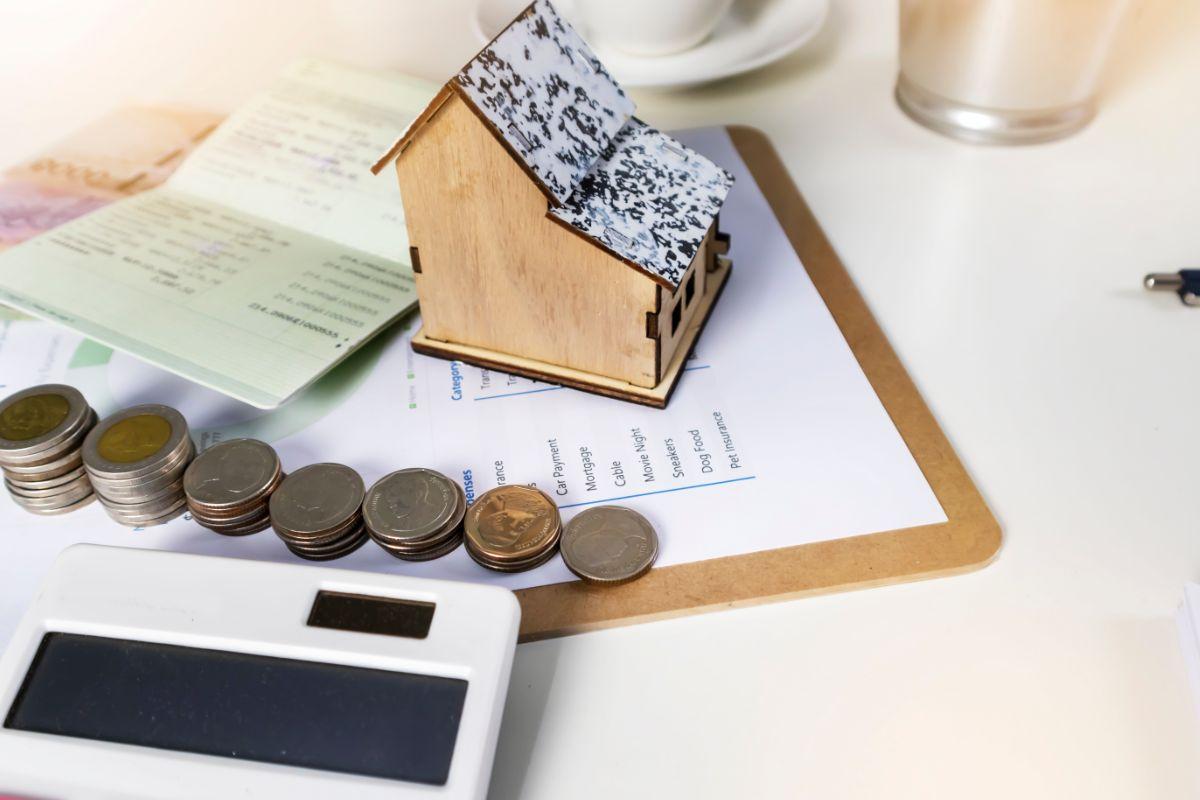 sagoma di casa, spiccioli e calcolatrice 