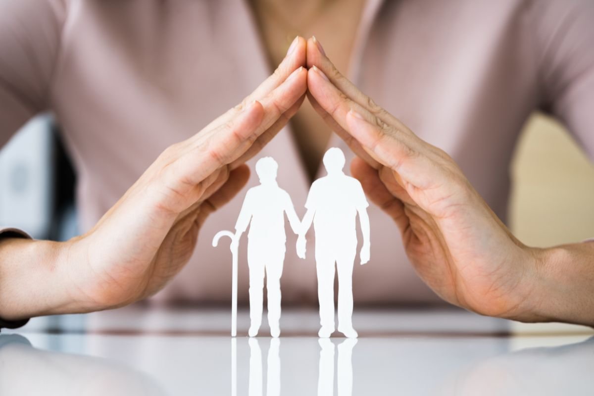 due mani a formare un triangolo e sotto due persone anziane fatte di carta