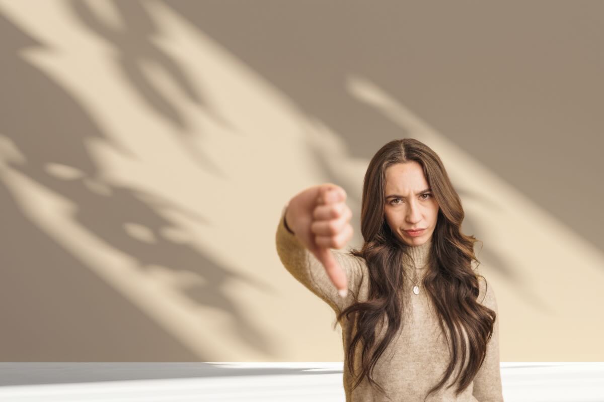 pareti beige e donna con pollice in giù 